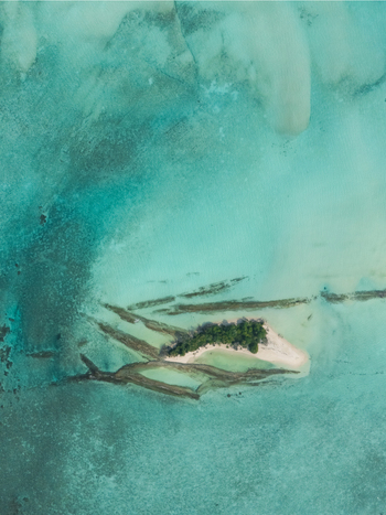 Aerial view of a small island with lush green trees surrounded by turquoise waters Thuraakunu Thiladhunmathee Uthuruburi Maldives. Aerial view of a small island with lush green trees surrounded by turquoise waters Thuraakunu Thiladhunmathee Uthuruburi Maldives.