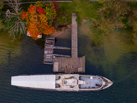 Aerial view of a boat moored at a wooden pier on the shore of a lake with vibrant autumn foliage in Trakai Vilnius County Lithuania. Aerial view of a boat moored at a wooden pier on the shore of a lake with vibrant autumn foliage in Trakai Vilnius County Lithuania.