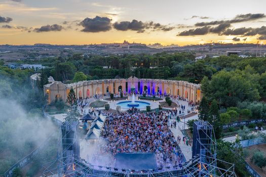 Attard Malta 20 September 2026 Aerial view of Park Nazzjonali Ta Qali during an outdoor music festival at sunset with a large crowd a central fountain and the historic skyline of Mdina. Attard Malta 20 September 2026 Aerial view of Park Nazzjonali Ta Qali during an outdoor music festival at sunset with a large crowd a central fountain and the historic skyline of Mdina.
