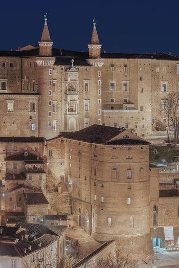 View of the illuminated Palazzo Ducale with its iconic towers and historic brick architecture at night in Urbino Marche Italy. View of the illuminated Palazzo Ducale with its iconic towers and historic brick architecture at night in Urbino Marche Italy.