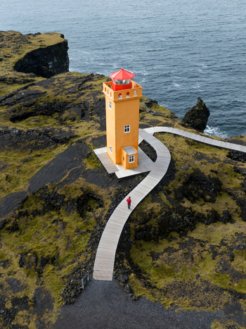 Aerial view of the vibrant Svörtuloft lighthouse standing bold against the rugged coastline with a winding boardwalk Svörtuloft Snæfellsbær Iceland. Aerial view of the vibrant Svörtuloft lighthouse standing bold against the rugged coastline with a winding boardwalk Svörtuloft Snæfellsbær Iceland.