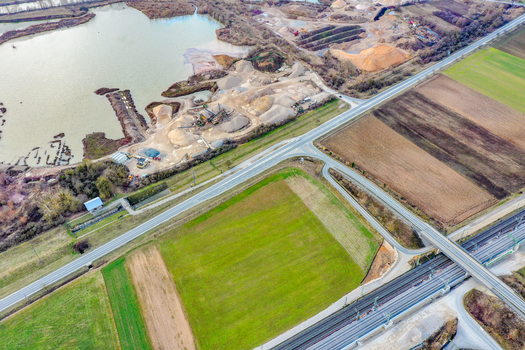 Aerial view of a gravel pit and industrial excavation site next to a lake agricultural fields and a road bridge Buttenheim Bavaria Germany. Aerial view of a gravel pit and industrial excavation site next to a lake agricultural fields and a road bridge Buttenheim Bavaria Germany.