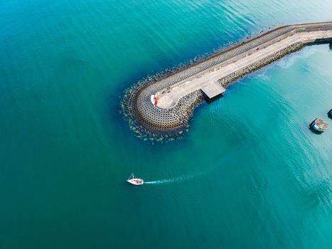 Aerial view of Bangor Harbour and Town with a small boat navigating the turquoise waters near the stone breakwater in Bangor Northern Ireland United Kingdom.