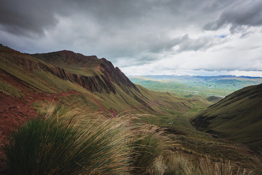 View of the dramatic ridges of Pallay Punchu Rainbow Mountain with colorful geological layers grassy foreground and a cloudy sky in Layo Cuzco Peru. View of the dramatic ridges of Pallay Punchu Rainbow Mountain with colorful geological layers grassy foreground and a cloudy sky in Layo Cuzco Peru.