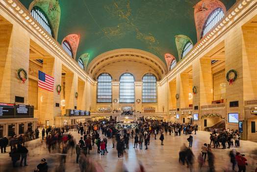 View of the bustling main concourse of Grand Central Terminal with its iconic celestial ceiling large arched windows and commuters in New York New York United States.