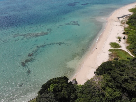 Aerial view of the Hyakume coastline featuring emerald green waters a white sandy beach and lush vegetation in Nanjo Okinawa Japan. Aerial view of the Hyakume coastline featuring emerald green waters a white sandy beach and lush vegetation in Nanjo Okinawa Japan.