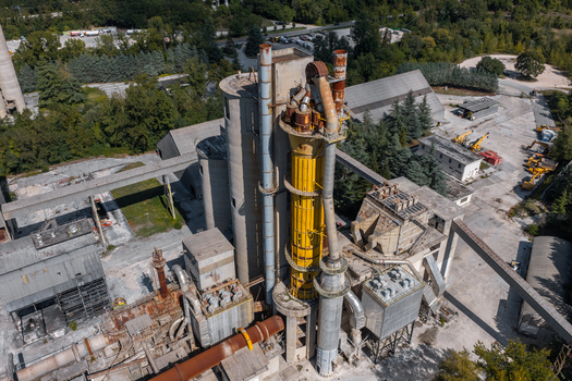 Aerial view of the Sacci S.P.A. cement factory featuring industrial silos a prominent yellow tower and metal pipes in Castelraimondo Marche Italy. Aerial view of the Sacci S.P.A. cement factory featuring industrial silos a prominent yellow tower and metal pipes in Castelraimondo Marche Italy.