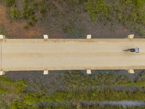 Aerial view of a cyclist riding a bicycle across a bridge over a marshy wetland area in Greyton Western Cape South Africa.