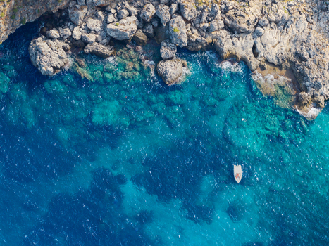 Aerial view of Riserva Naturale Orientata dello Zingaro with rugged cliffs meeting turquoise waters and a small boat floating near San Vito Lo Capo Sicilia Italy. Aerial view of Riserva Naturale Orientata dello Zingaro with rugged cliffs meeting turquoise waters and a small boat floating near San Vito Lo Capo Sicilia Italy.