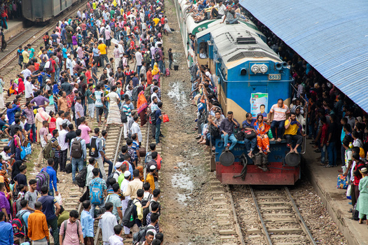 Dhaka Bangladesh 15 June 2018 View of Airport Railway Station crowded with people on platforms and a blue train covered with passengers sitting on the roof and sides. Dhaka Bangladesh 15 June 2018 View of Airport Railway Station crowded with people on platforms and a blue train covered with passengers sitting on the roof and sides.