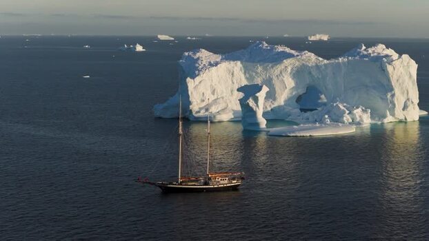 Aerial view of sailboat near arch iceberg in Greenland. Aerial view of sailboat near arch iceberg in Greenland.