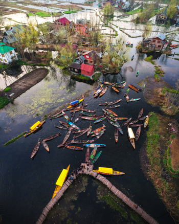 Aerial view of Dal Lake with numerous traditional shikara boats navigating through the calm waters surrounded by colorful houseboats and lush greenery in Srinagar Kashmir India. Aerial view of Dal Lake with numerous traditional shikara boats navigating through the calm waters surrounded by colorful houseboats and lush greenery in Srinagar Kashmir India.