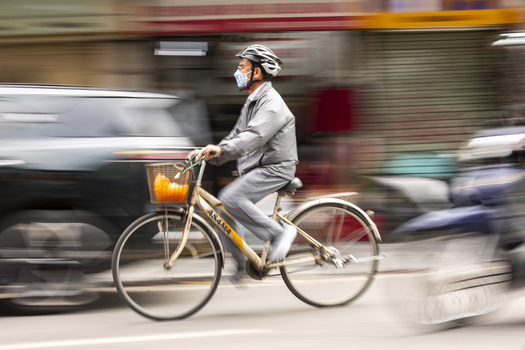 Hanoi Vietnam 11 November 2025 View of a man riding a bicycle through city traffic with motion blur.