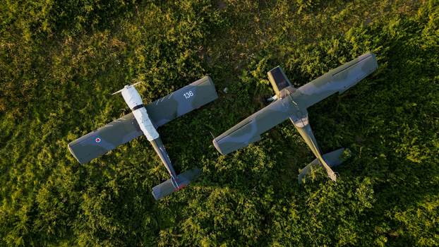 Serbia 03 September 2023 Aerial view of two military aircraft parked in a grassy field with camouflage patterns and visible markings under the warm light of the golden hour.