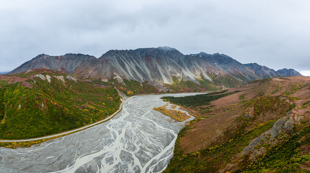 Aerial view of Rainbow Ridge featuring a wide braided river winding through rugged mountains with vibrant autumn foliage in Southeast Fairbanks Census Area Alaska United States. Aerial view of Rainbow Ridge featuring a wide braided river winding through rugged mountains with vibrant autumn foliage in Southeast Fairbanks Census Area Alaska United States.