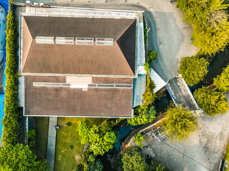 Aerial view of The Pavilion Venue with its brown roof surrounded by lush greenery trees and a small stream in Kecamatan Ciputat Timur Banten Indonesia. Aerial view of The Pavilion Venue with its brown roof surrounded by lush greenery trees and a small stream in Kecamatan Ciputat Timur Banten Indonesia.