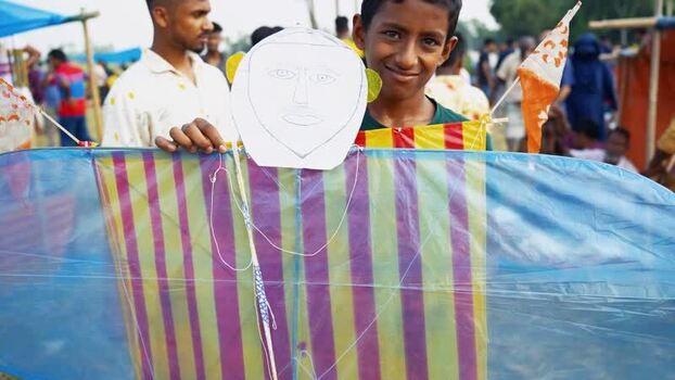 View of a young boy holding a large colorful kite Bangladesh. View of a young boy holding a large colorful kite Bangladesh.