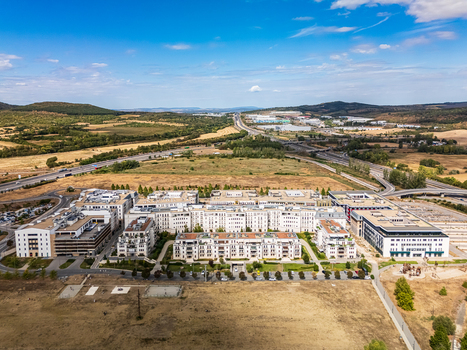 Aerial view of the Topark residential complex beside the M0 and M1 highway interchange with apartment blocks offices dry fields and wooded hills in Biatorbagy Hungary. Aerial view of the Topark residential complex beside the M0 and M1 highway interchange with apartment blocks offices dry fields and wooded hills in Biatorbagy Hungary.