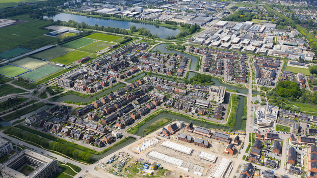 Aerial view of modern residential neighborhood with brick houses winding canals and sports fields under a clear sky in Utrecht Utrecht Netherlands. Aerial view of modern residential neighborhood with brick houses winding canals and sports fields under a clear sky in Utrecht Utrecht Netherlands.