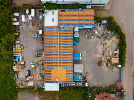 Aerial view of Neuenstein Techno Zone featuring a large industrial building with solar panels surrounded by storage areas with equipment and vehicles in Neuenstein Baden Wurttemberg Germany. Aerial view of Neuenstein Techno Zone featuring a large industrial building with solar panels surrounded by storage areas with equipment and vehicles in Neuenstein Baden Wurttemberg Germany.