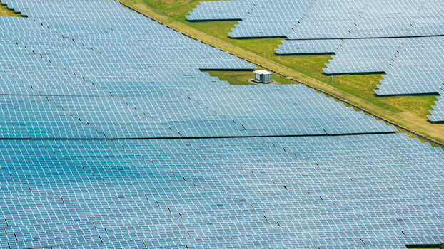 Aerial view of a large solar farm with rows of photovoltaic panels arranged in a grid pattern across green fields in Bais City Negros Island Region Philippines. Aerial view of a large solar farm with rows of photovoltaic panels arranged in a grid pattern across green fields in Bais City Negros Island Region Philippines.