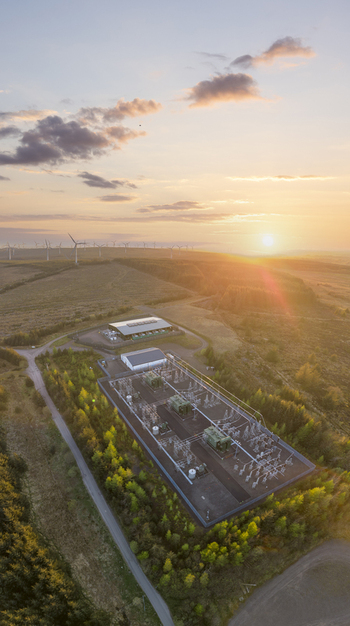 Aerial view of an electrical substation on Eaglesham Moor with wind turbines on the horizon under a golden sunset in Kilmarnock Scotland United Kingdom.