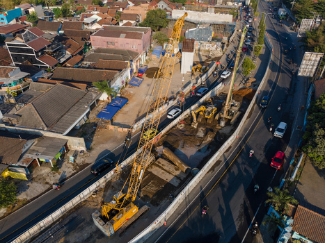 Aerial view of a construction site with a large yellow crane heavy machinery and road works near residential buildings and traffic in Yogyakarta Special Region of Yogyakarta Indonesia. Aerial view of a construction site with a large yellow crane heavy machinery and road works near residential buildings and traffic in Yogyakarta Special Region of Yogyakarta Indonesia.