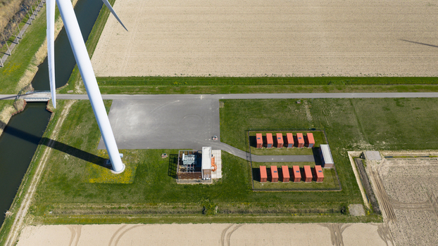 Aerial view of a wind turbine base electrical substation and red battery storage units in a rural landscape Middelharnis South Holland Netherlands. Aerial view of a wind turbine base electrical substation and red battery storage units in a rural landscape Middelharnis South Holland Netherlands.