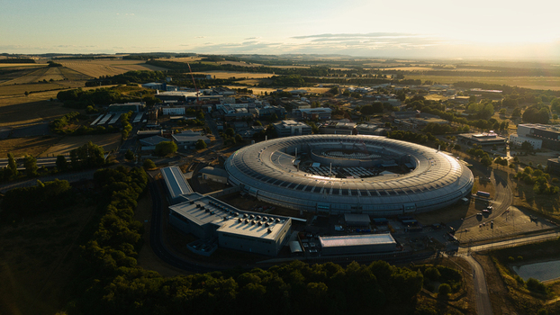 Aerial view of Diamond Light Source a circular synchrotron facility surrounded by greenery under golden hour light in Didcot United Kingdom.