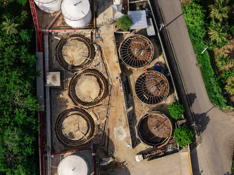 Aerial view of industrial storage tanks and construction site with circular foundations and metal framework in Bajos de Haina San Cristobal Province Dominican Republic.