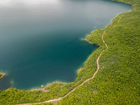 Aerial view of Slansko Lake with a winding dirt path along the lush green forested shoreline in Niksic Municipality Montenegro. Aerial view of Slansko Lake with a winding dirt path along the lush green forested shoreline in Niksic Municipality Montenegro.