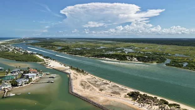 Aerial view of Matanzas Inlet featuring turquoise waters sandy beaches and lush marshlands under a bright blue sky in St. Johns County Florida United States. Aerial view of Matanzas Inlet featuring turquoise waters sandy beaches and lush marshlands under a bright blue sky in St. Johns County Florida United States.