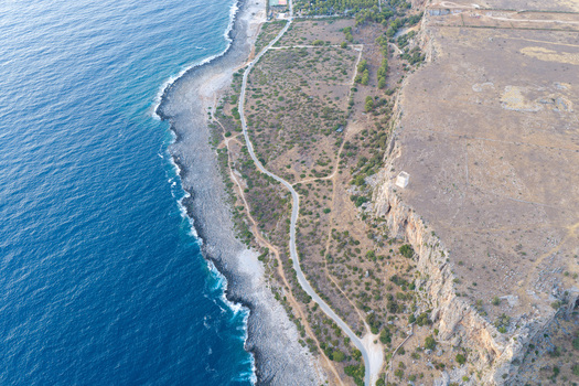 Aerial view of Riserva Naturale Orientata dello Zingaro featuring rugged cliffs a coastal road Mediterranean vegetation and the blue Tyrrhenian Sea in San Vito Lo Capo Sicilia Italy. Aerial view of Riserva Naturale Orientata dello Zingaro featuring rugged cliffs a coastal road Mediterranean vegetation and the blue Tyrrhenian Sea in San Vito Lo Capo Sicilia Italy.