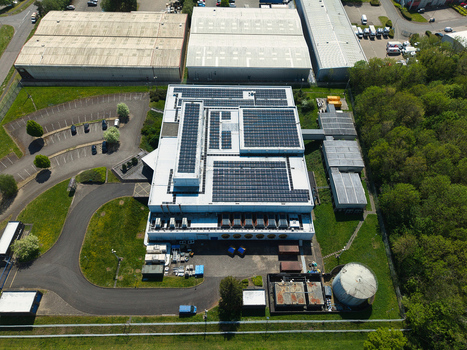 Aerial view of a modern data centre featuring extensive solar panel arrays on the roof surrounded by industrial warehouses and lush green trees in Wellingborough England United Kingdom. Aerial view of a modern data centre featuring extensive solar panel arrays on the roof surrounded by industrial warehouses and lush green trees in Wellingborough England United Kingdom.