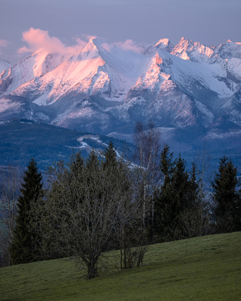 View of the snow capped Tatra Mountains at sunset with pink light on the peaks and green hills in Czarna Gora Lesser Poland Poland. View of the snow capped Tatra Mountains at sunset with pink light on the peaks and green hills in Czarna Gora Lesser Poland Poland.