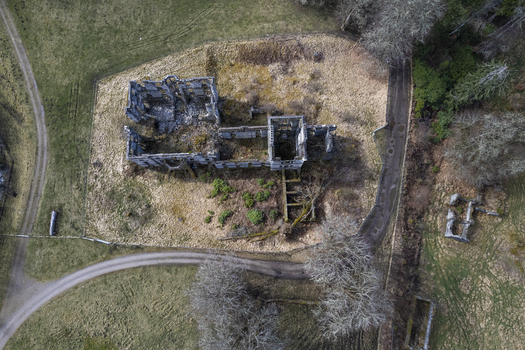 Aerial view of the ruins of Guisachan Historic House showing stone walls and foundations surrounded by grassy fields and a winding path in Beauly Glen Affric Scotland United Kingdom. Aerial view of the ruins of Guisachan Historic House showing stone walls and foundations surrounded by grassy fields and a winding path in Beauly Glen Affric Scotland United Kingdom.
