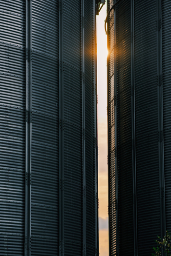 View of sunbeams piercing through the narrow gap between two towering textured grain silos creating a striking contrast of light and shadow Sremska Mitrovica Vojvodina Serbia. View of sunbeams piercing through the narrow gap between two towering textured grain silos creating a striking contrast of light and shadow Sremska Mitrovica Vojvodina Serbia.