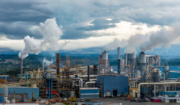 Aerial view of industrial complex billowing smoke into the cloudy sky a stark contrast against the distant hills Medell&iacute;n Colombia.