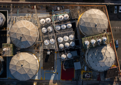 Aerial view of the beer industrial complex featuring large circular storage tanks and intricate piping systems on a concrete facility in Santo Domingo Dominican Republic. Aerial view of the beer industrial complex featuring large circular storage tanks and intricate piping systems on a concrete facility in Santo Domingo Dominican Republic.
