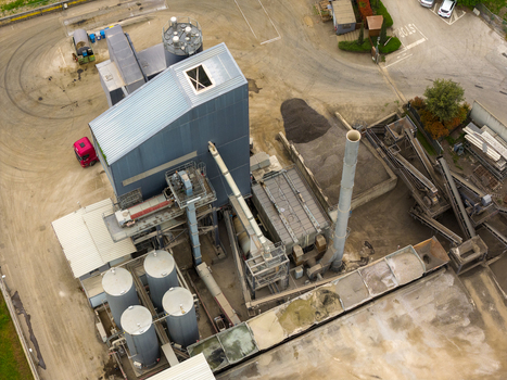 Aerial view of an industrial asphalt plant with large metal silos conveyor belts and piles of raw materials San Giovanni Valdarno Tuscany Italy.