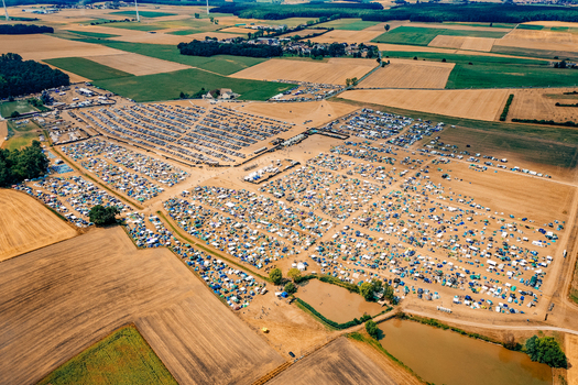 Herzogenaurach Germany 22 July 2022 Aerial view of the Open Beatz Festival campsite with numerous tents and parked cars surrounded by vast agricultural fields and green forests. Herzogenaurach Germany 22 July 2022 Aerial view of the Open Beatz Festival campsite with numerous tents and parked cars surrounded by vast agricultural fields and green forests.