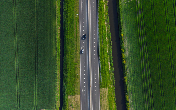 Aerial view of a straight highway with cars driving between lush green agricultural fields and narrow canals Vierpolders South Holland Netherlands. Aerial view of a straight highway with cars driving between lush green agricultural fields and narrow canals Vierpolders South Holland Netherlands.