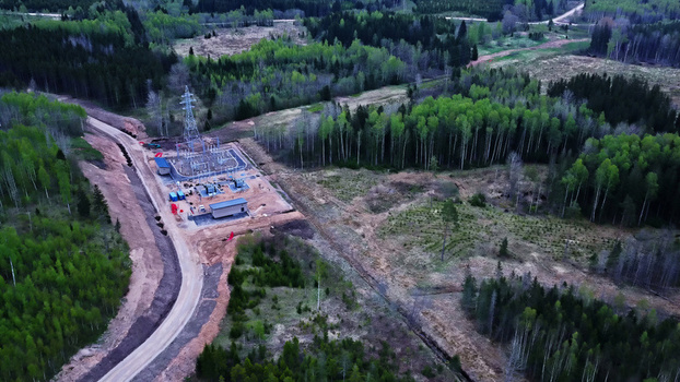Aerial view of an electrical substation situated in a forest clearing with a dirt road and power lines in Latvia. Aerial view of an electrical substation situated in a forest clearing with a dirt road and power lines in Latvia.