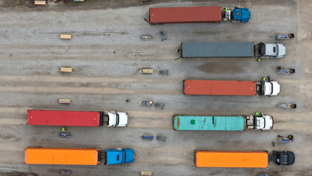 Aerial view of semi trucks with colorful shipping containers parked in rows on a gravel logistics yard in Columbus Ohio United States.