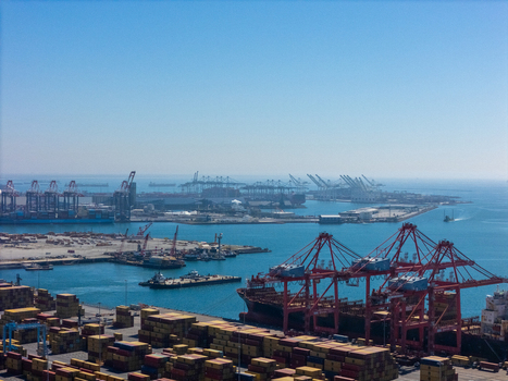 Aerial view of the Port of Long Beach with large container ships red gantry cranes and stacked shipping containers under a clear blue sky in Long Beach California United States. Aerial view of the Port of Long Beach with large container ships red gantry cranes and stacked shipping containers under a clear blue sky in Long Beach California United States.
