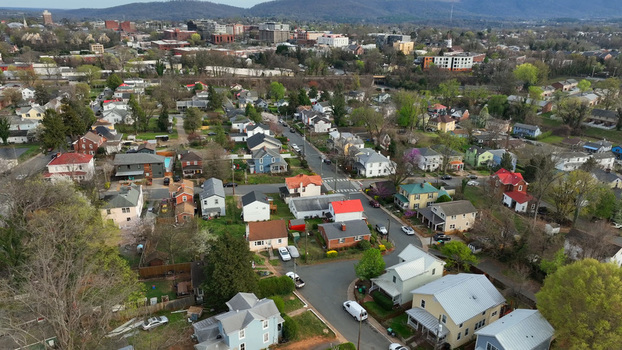 Aerial view of residential neighborhood with houses tree lined streets and distant city skyline in Charlottesville Virginia United States.