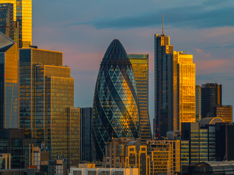 Aerial view of The Gherkin in the City of London financial district illuminated by golden sunset light surrounded by modern glass office towers London England United Kingdom.