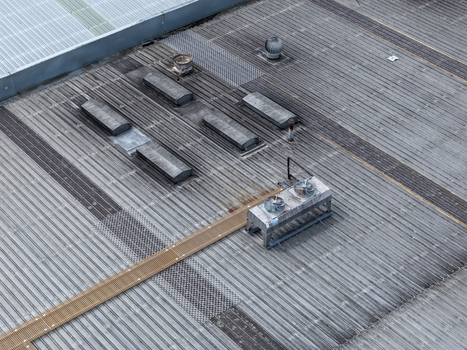 Melbourne Australia 25 September 2026 Aerial view of the industrial roof of a factory featuring metallic corrugated surfaces ventilation units and cooling fans.