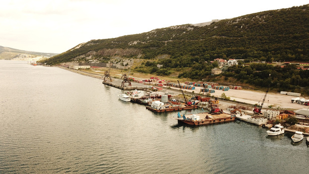 Aerial view of industrial port facilities with cranes barges and small boats moored along the coastline in Bakarac Primorje Gorski Kotar Croatia. Aerial view of industrial port facilities with cranes barges and small boats moored along the coastline in Bakarac Primorje Gorski Kotar Croatia.
