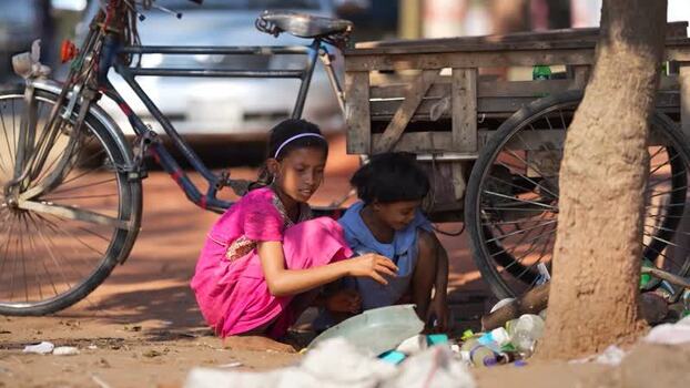 View of two young girls sitting by a bicycle and cart Bangladesh.